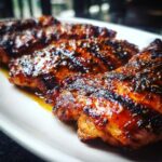 Close-up of Huli Huli Grilled Chicken pieces on a white plate, showing the caramelized glaze.
