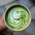 Top-down view of a vibrant Iced Matcha Latte Coconut Milk drink with a beautiful swirl pattern.