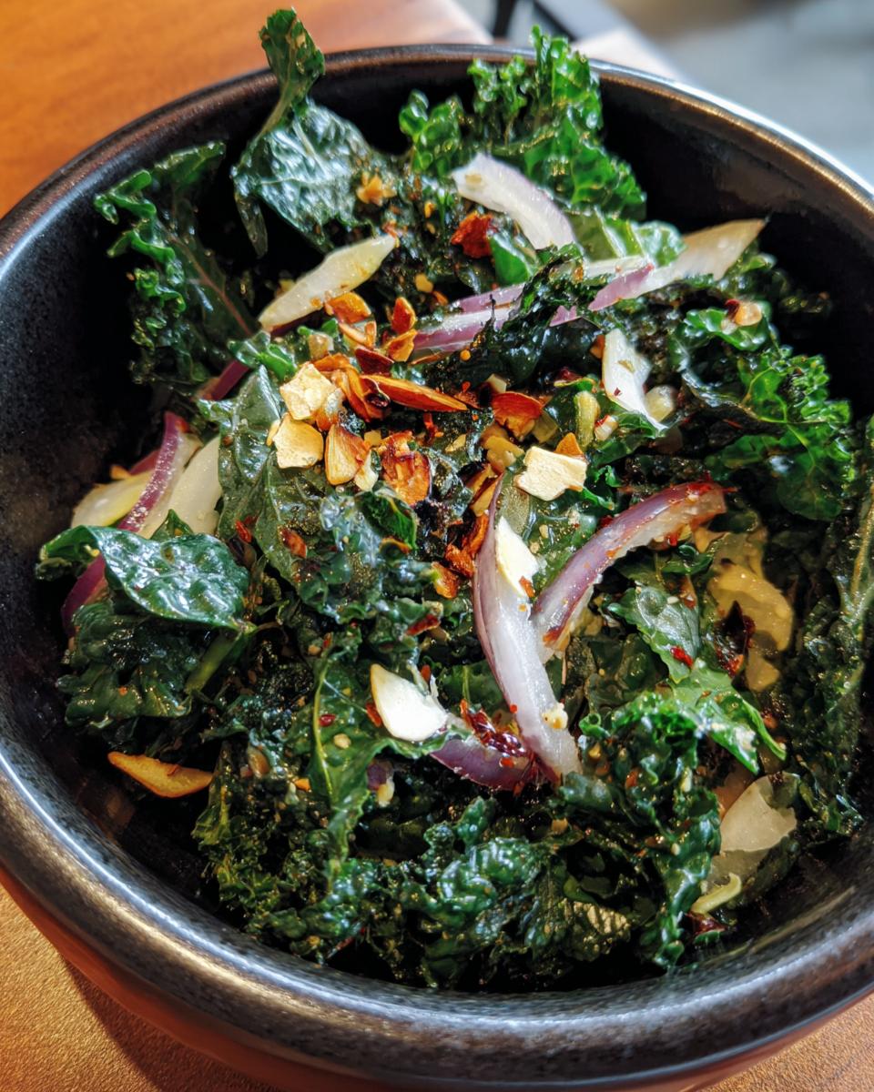 A bowl of vibrant Kale Crunch Salad with kale, red onions, and toasted almonds.