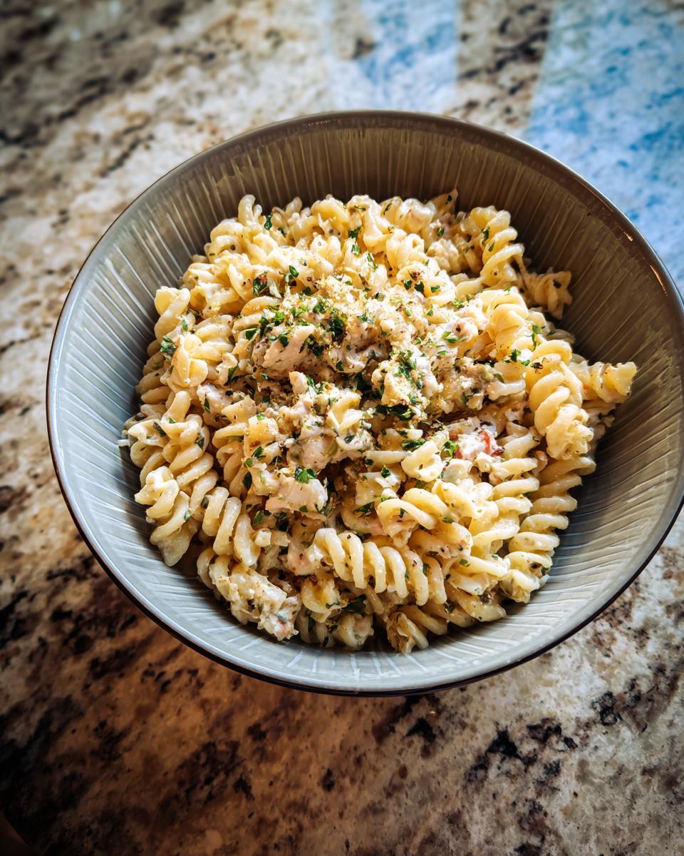 Overhead shot of Lemon Basil Pasta Salad in a bowl, garnished with fresh herbs.