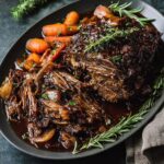 A platter of Mississippi Pot Roast with carrots, onions, and herbs, served in a rich sauce.