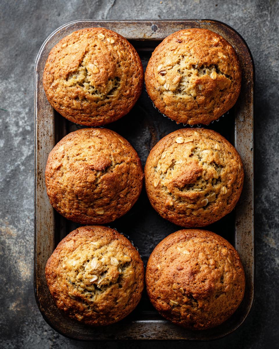 Six One-Bowl Ultra Moist Banana Oatmeal Muffins in a metal muffin pan, ready to eat.