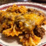 A serving of One-Pot Cheesy Taco Pasta with bowtie pasta, ground beef, taco seasoning, and melted cheese on a plate.