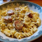 A bowl of One Pot Creamy Kielbasa Pasta, featuring spiral pasta, sliced kielbasa, creamy sauce, and herbs.