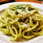 A plate of delicious One-Pot Creamy Pesto Pasta, topped with parmesan cheese and herbs.