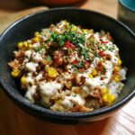 A delicious Packed Street Corn Chicken Rice Bowl topped with sauce, corn, and herbs.