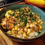 A delicious Packed Street Corn Chicken Rice Bowl with rice, corn, chicken, and herbs in a blue bowl.