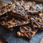 Close-up of 10-Minute No-Bake Peanut Butter Pretzel Bark pieces, drizzled with chocolate and sprinkled with sea salt.