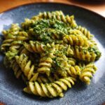 Close-up of Pesto Pasta Salad with spiral pasta, vibrant green pesto, and fresh herb garnish.