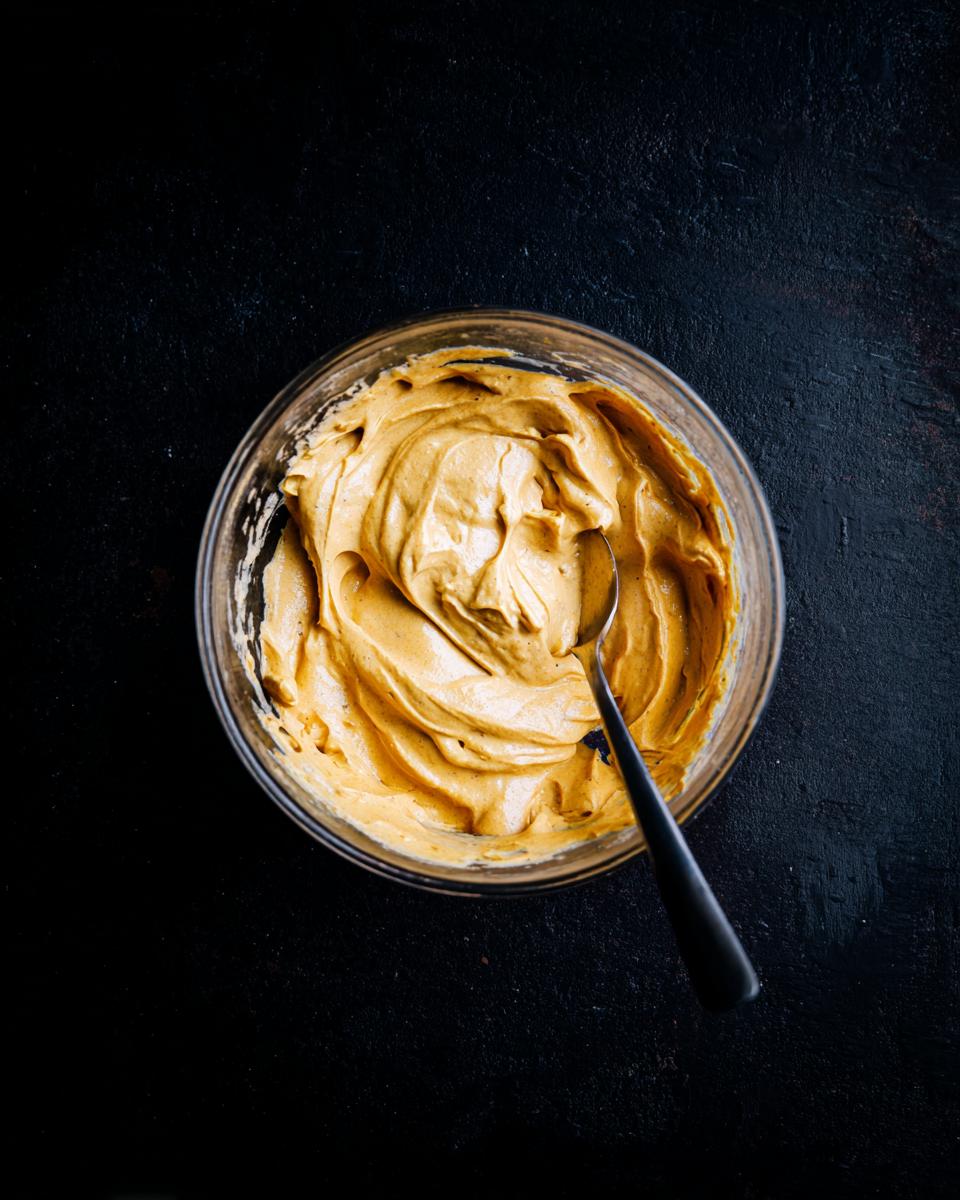 Overhead shot of The Pumpkin Fluff in a clear glass bowl with a spoon, ready to serve.