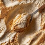 Close-up of a spoonful of The Pumpkin Fluff, a light and airy dessert, sprinkled with spices.