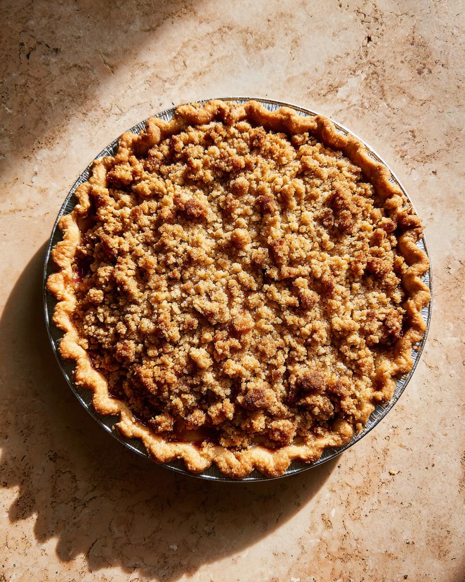 Overhead shot of a whole The Rhubarb Crisp pie with a golden-brown crumble topping in a tin pan.