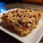A slice of The Rhubarb Crisp on a white plate, showing the rhubarb filling and crumb topping.