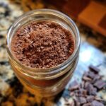Overhead shot of a jar filled with Rich & Creamy Homemade Hot Cocoa Mix, topped with chocolate shavings.