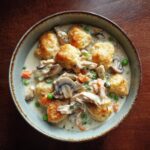 Overhead shot of a bowl of Ultimate Slow-Cooker Chicken Pot Pie with dumplings, chicken, peas, carrots, and mushrooms.