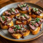 A plate of delicious 30-Min Gourmet Steak Crostini Bites, topped with sauce and herbs.