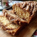 Two slices of super moist cinnamon apple bread with glaze, resting on a wooden board.