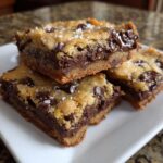 A stack of three Ultimate Melt-in-Your-Mouth Chocolate Chip Cookie Bars, topped with sea salt.