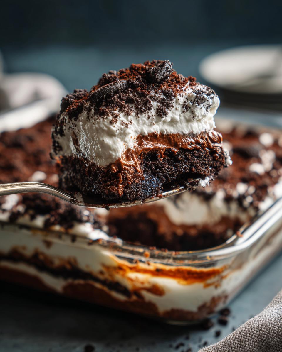 A spoonful of Ultimate No-Bake Dirt Cake showing layers of chocolate, cream, and crushed cookies.