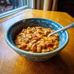 A bowl of Vegan Tomato White Bean Stew with a spoon, showcasing the rich texture and vibrant colors.