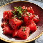 Close-up of a refreshing Watermelon Salad in a bowl, garnished with fresh mint and sesame seeds.